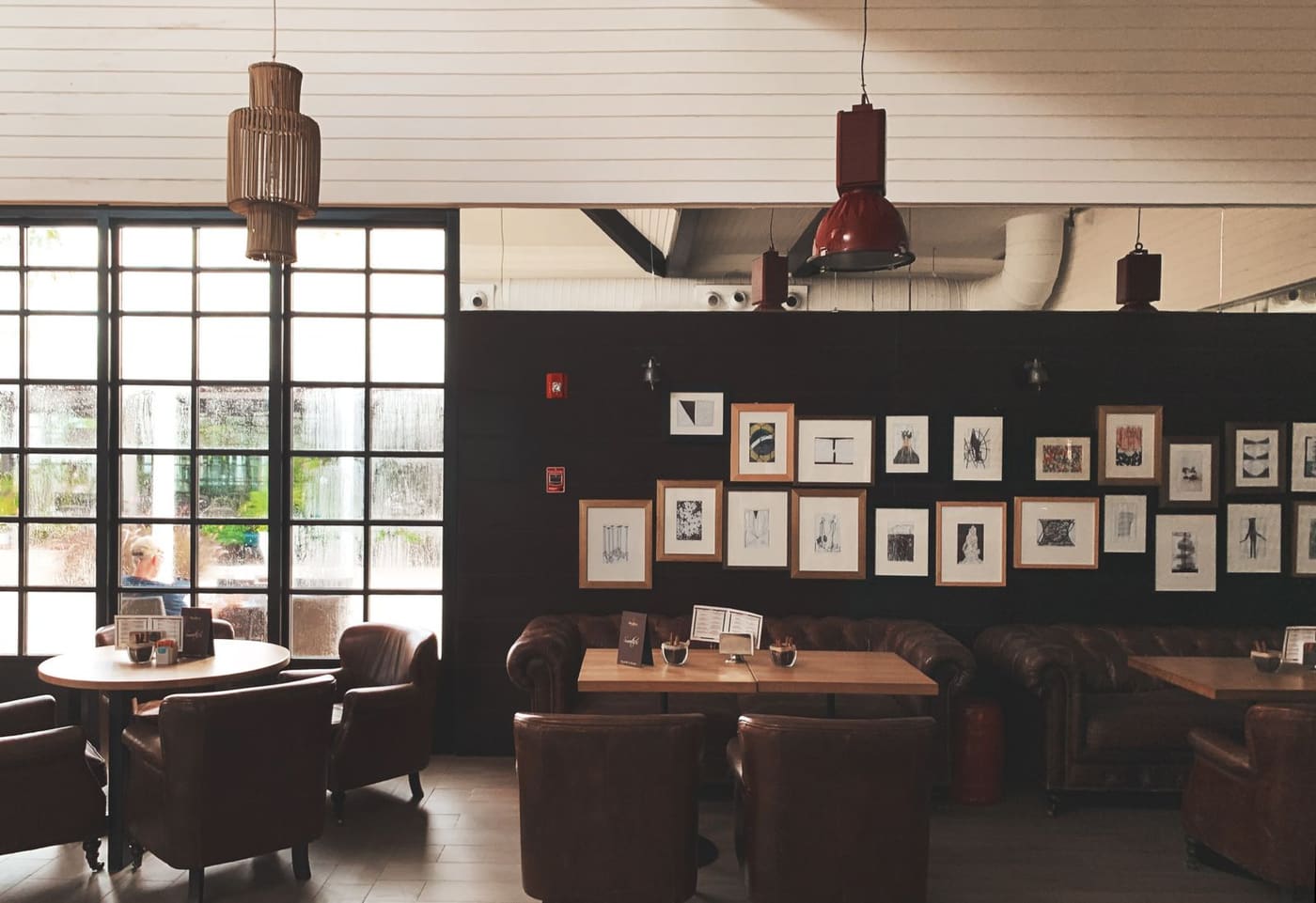 Warm, softly lit interior of Maple & Bean café with leather armchairs and a gallery wall